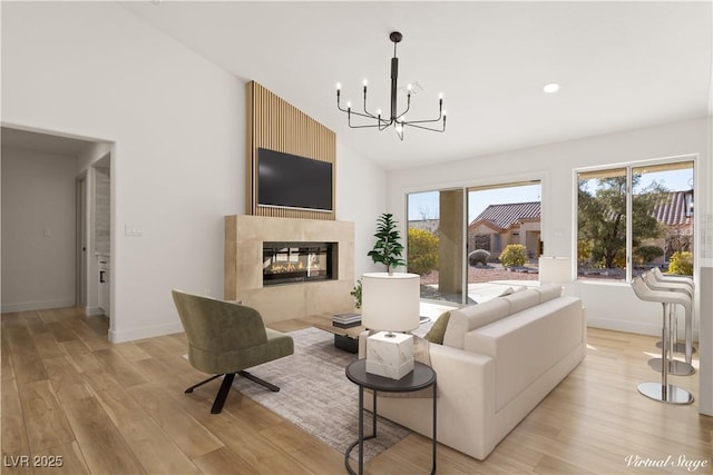 living room featuring light hardwood / wood-style flooring, an inviting chandelier, vaulted ceiling, and a fireplace