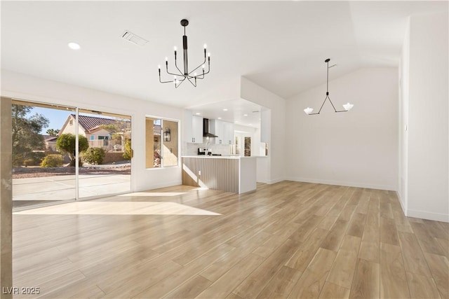 unfurnished living room featuring vaulted ceiling, a notable chandelier, and light hardwood / wood-style flooring