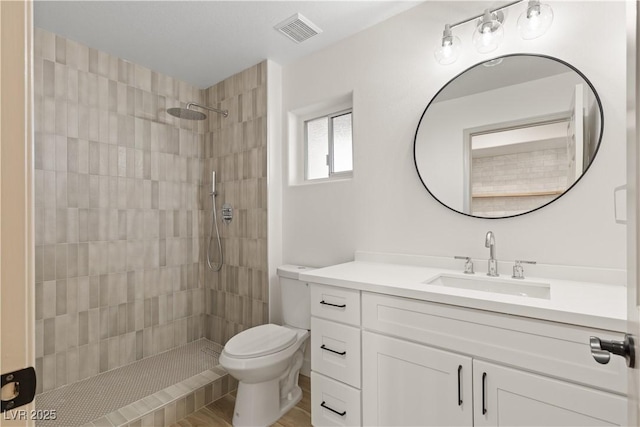 bathroom featuring tiled shower, vanity, and toilet