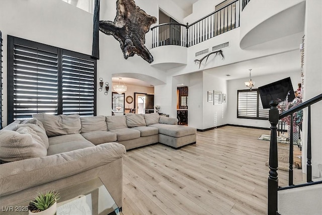 living room with a high ceiling, a notable chandelier, and light hardwood / wood-style floors