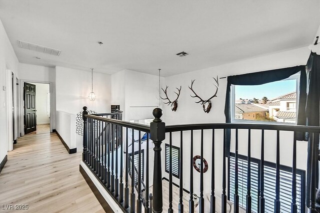 hallway with light wood-type flooring and a notable chandelier