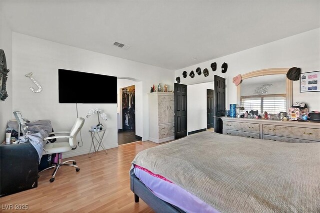 bedroom with a walk in closet, hardwood / wood-style floors, and a closet