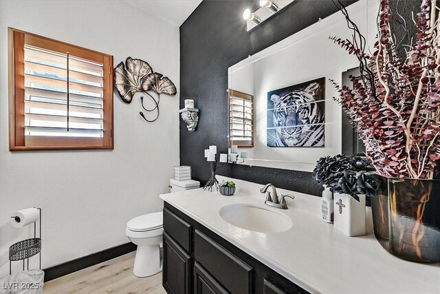 bathroom with a healthy amount of sunlight, vanity, hardwood / wood-style flooring, and toilet