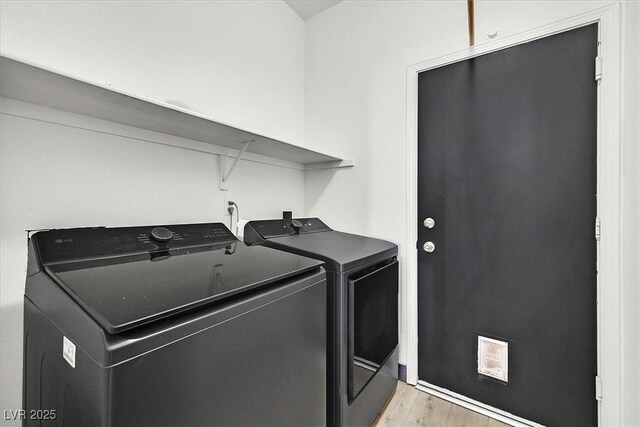 laundry area with washing machine and clothes dryer and light hardwood / wood-style flooring