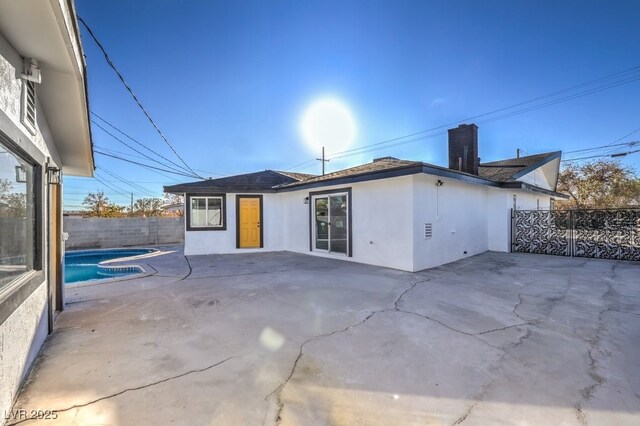 rear view of property featuring a fenced in pool and a patio area