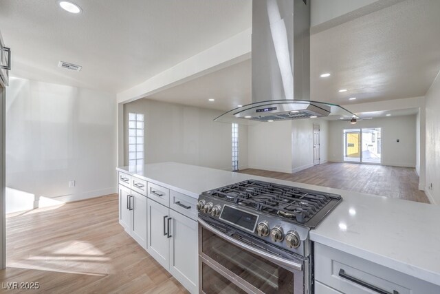 kitchen featuring white cabinetry, ceiling fan, light hardwood / wood-style floors, island exhaust hood, and range with two ovens