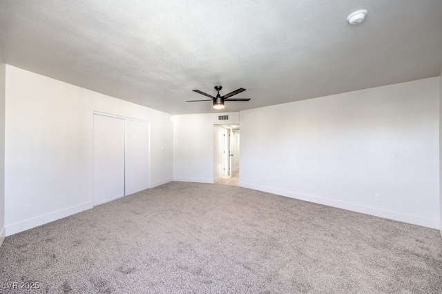 carpeted spare room featuring a textured ceiling and ceiling fan