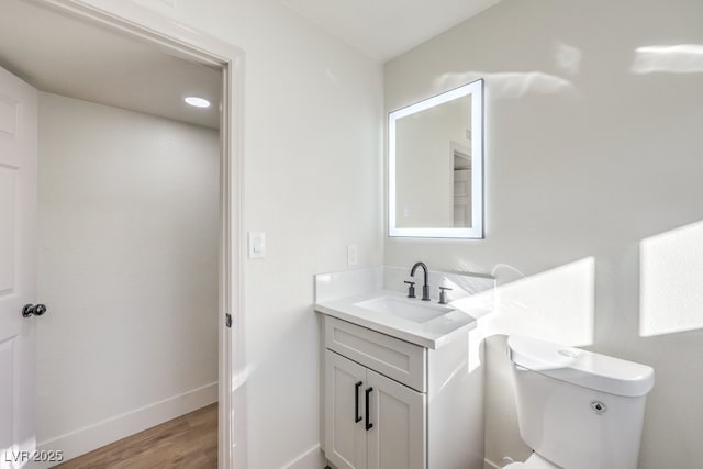 bathroom featuring toilet, vanity, and hardwood / wood-style flooring