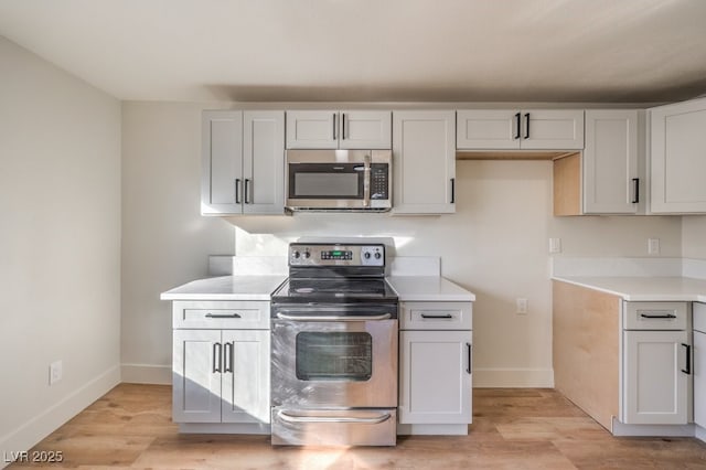 kitchen with appliances with stainless steel finishes, light hardwood / wood-style flooring, and white cabinets