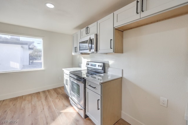 kitchen featuring appliances with stainless steel finishes, light hardwood / wood-style flooring, and white cabinets