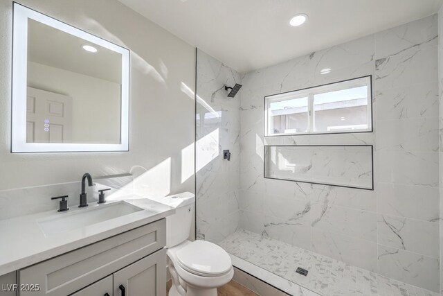 bathroom featuring tiled shower, vanity, and toilet