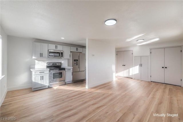 kitchen with appliances with stainless steel finishes and light hardwood / wood-style floors