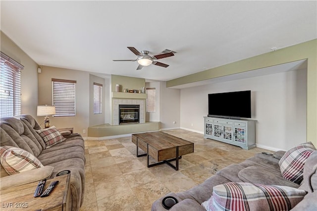 living room with a tiled fireplace and ceiling fan