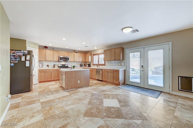 kitchen featuring stainless steel appliances, french doors, a center island, and light brown cabinetry