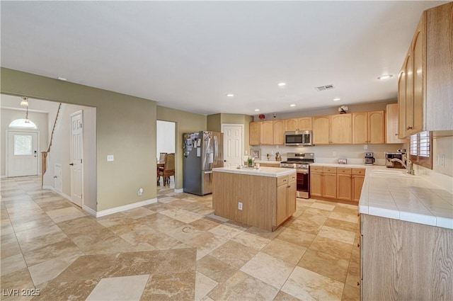 kitchen featuring sink, appliances with stainless steel finishes, light brown cabinets, and a center island