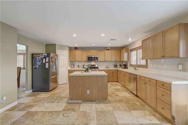 kitchen featuring stainless steel appliances, a center island, sink, and light brown cabinetry