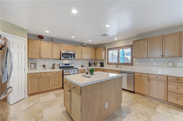 kitchen featuring sink, tile countertops, light brown cabinets, a kitchen island, and appliances with stainless steel finishes