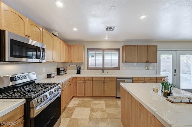 kitchen featuring appliances with stainless steel finishes, a wealth of natural light, sink, and tile counters