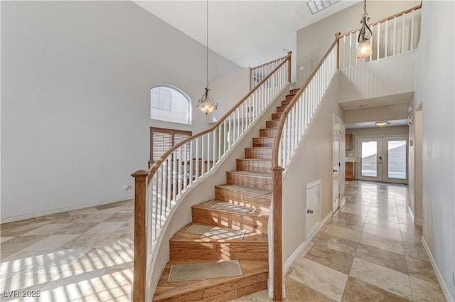 stairs with french doors, a high ceiling, and an inviting chandelier