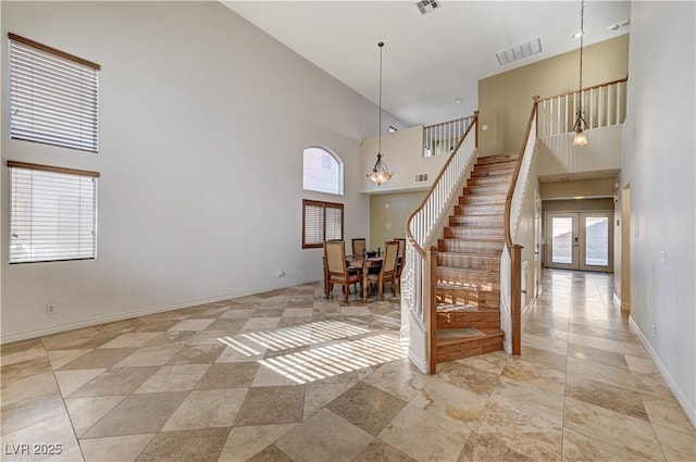 interior space with a high ceiling, french doors, and a chandelier