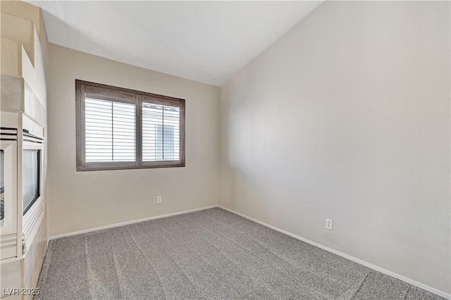 carpeted spare room featuring vaulted ceiling