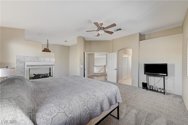 carpeted bedroom featuring ceiling fan and a fireplace