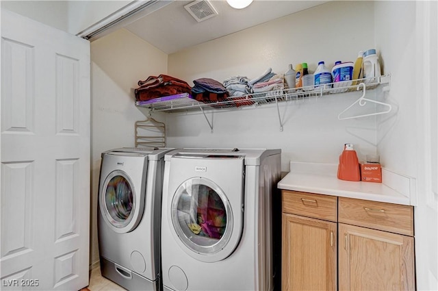 laundry area featuring separate washer and dryer and cabinets