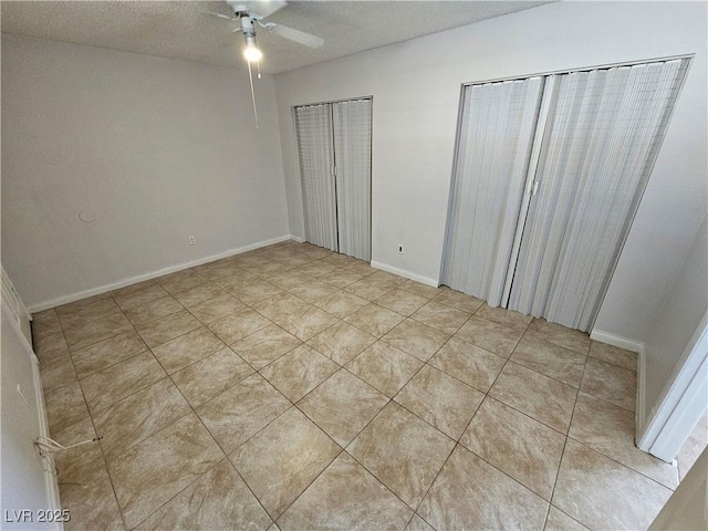 unfurnished bedroom featuring ceiling fan, multiple closets, light tile patterned flooring, and a textured ceiling