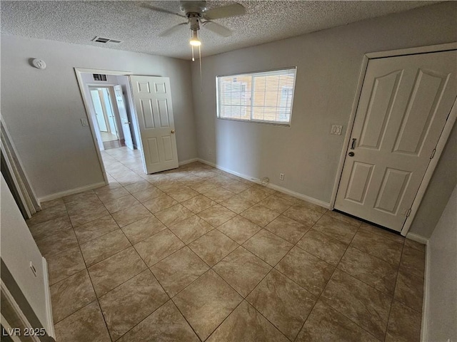 tiled empty room with ceiling fan and a textured ceiling