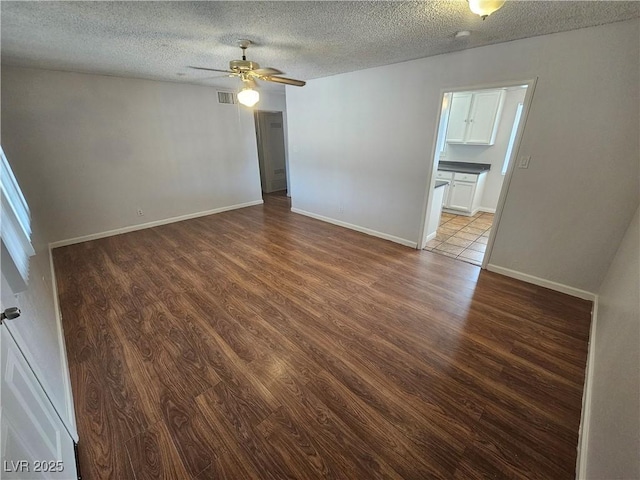 spare room with dark wood-type flooring, a textured ceiling, and ceiling fan