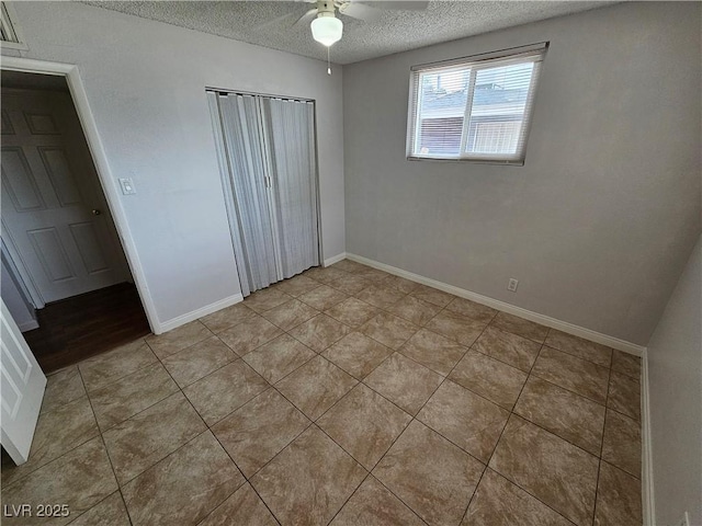 unfurnished bedroom with a textured ceiling, ceiling fan, light tile patterned floors, and a closet