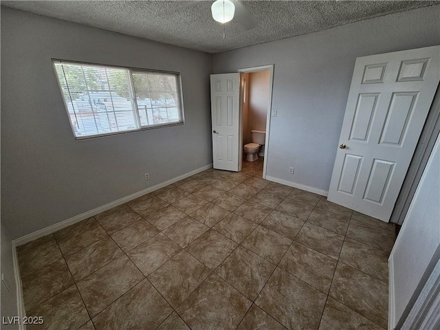 unfurnished bedroom with a textured ceiling, ensuite bathroom, and tile patterned flooring