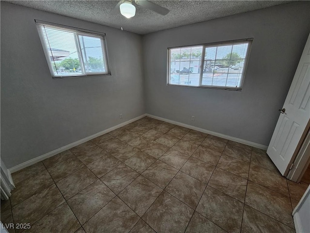 unfurnished room with a textured ceiling, ceiling fan, and dark tile patterned floors