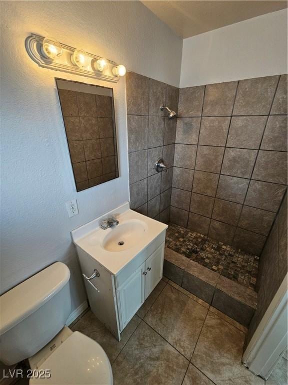 bathroom featuring toilet, tiled shower, and vanity