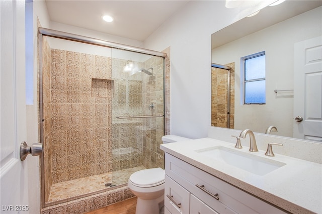 bathroom featuring a shower with door, hardwood / wood-style flooring, vanity, and toilet