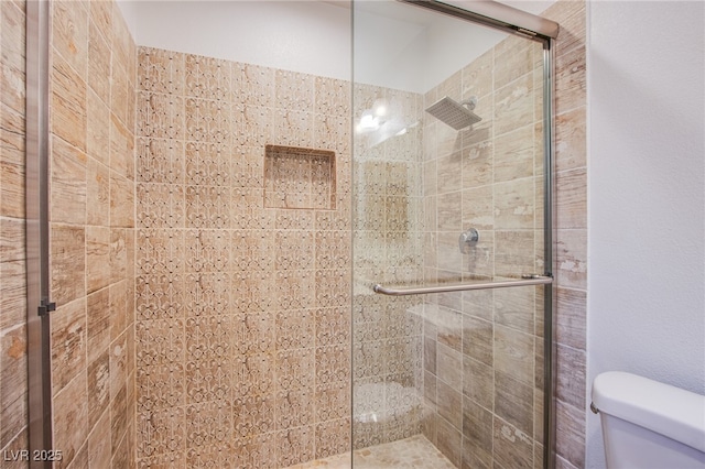 bathroom featuring toilet and a shower with shower door