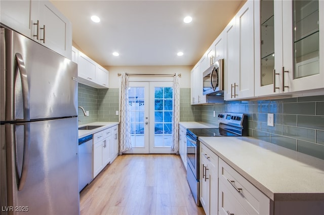 kitchen featuring sink, white cabinets, french doors, backsplash, and appliances with stainless steel finishes