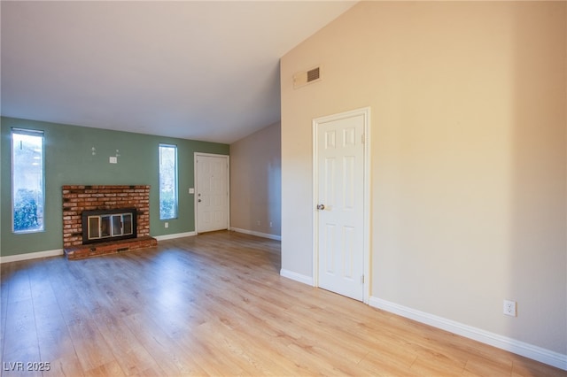 unfurnished living room featuring lofted ceiling, a fireplace, and light wood-type flooring