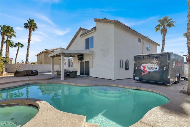 back of property featuring a swimming pool with hot tub and a patio area