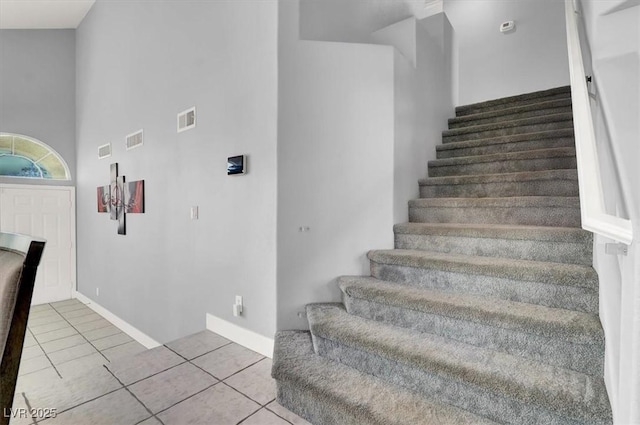 stairs featuring a towering ceiling and tile patterned floors