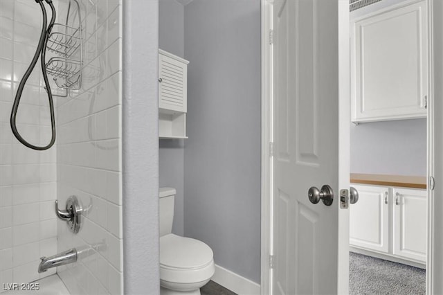 bathroom featuring toilet and tiled shower / bath combo