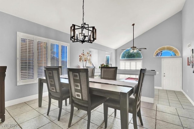 tiled dining space featuring ceiling fan with notable chandelier and high vaulted ceiling