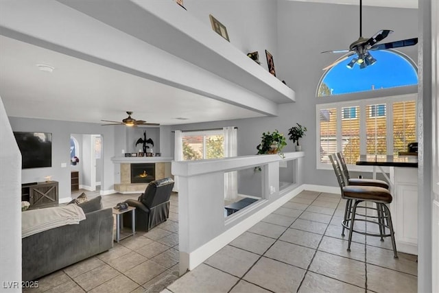 tiled living room with ceiling fan and high vaulted ceiling