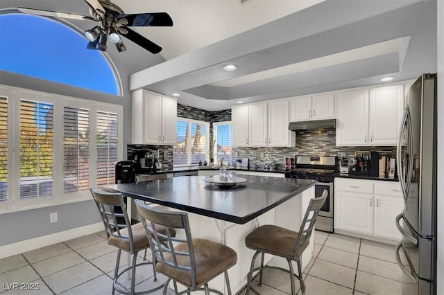 kitchen with ceiling fan, stainless steel appliances, white cabinetry, and light tile patterned flooring