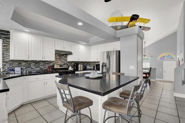 kitchen featuring white cabinets, stainless steel appliances, light tile patterned flooring, and a kitchen breakfast bar