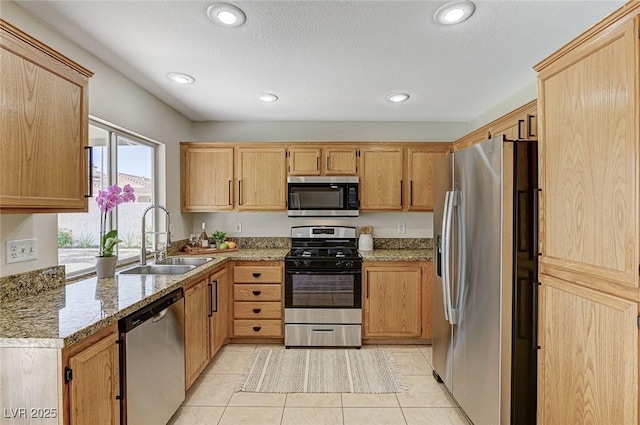 kitchen with stainless steel appliances, light tile patterned flooring, sink, and light stone counters