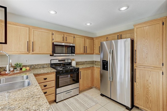 kitchen featuring light stone counters, sink, light tile patterned floors, appliances with stainless steel finishes, and light brown cabinets