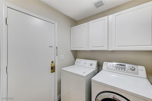 clothes washing area with washer and dryer and cabinets