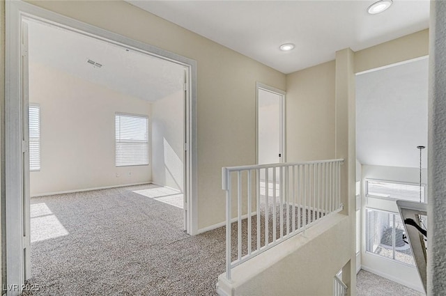 hall featuring light carpet, a wealth of natural light, and lofted ceiling