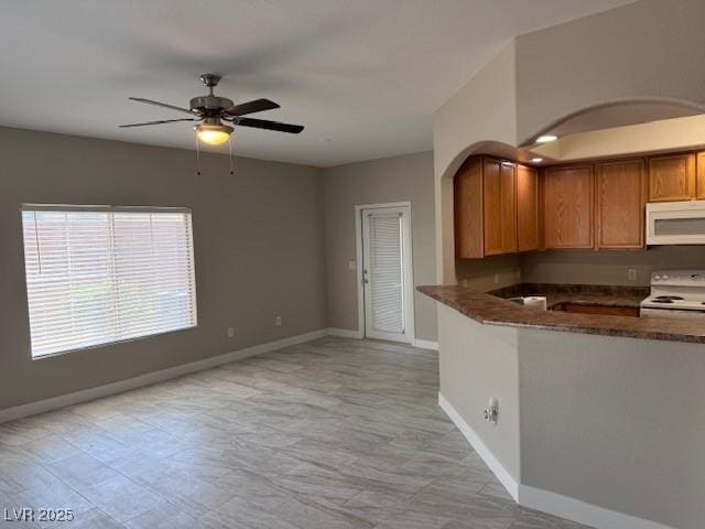 kitchen with white appliances, ceiling fan, and dark stone countertops